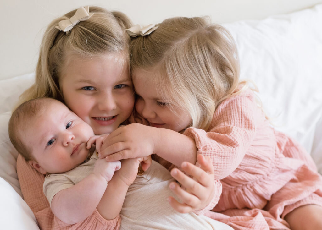two little girls holding baby brother