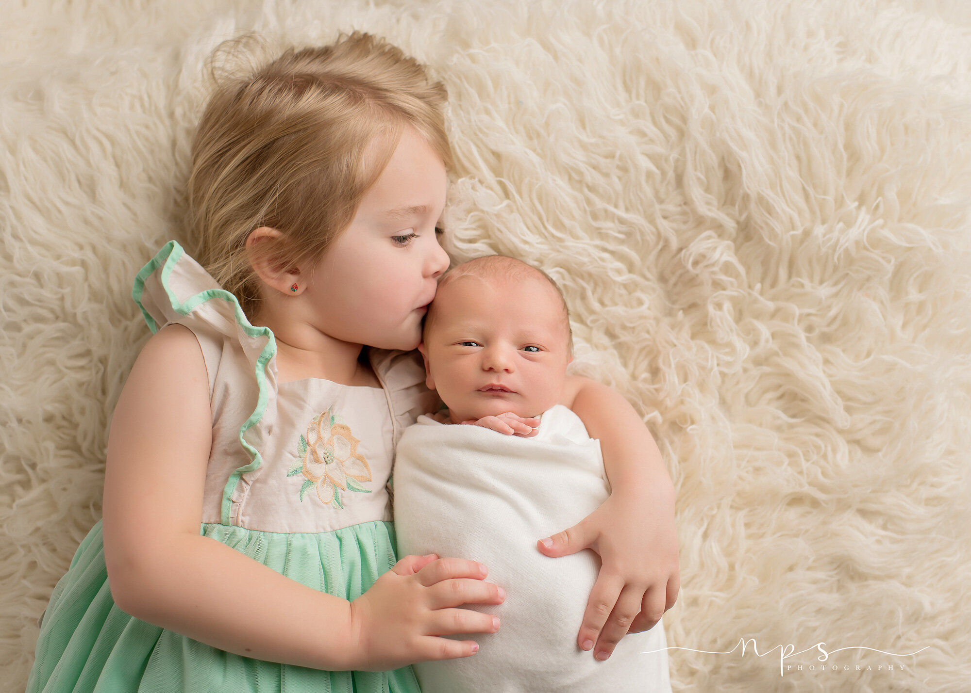 sister kissing newborn
