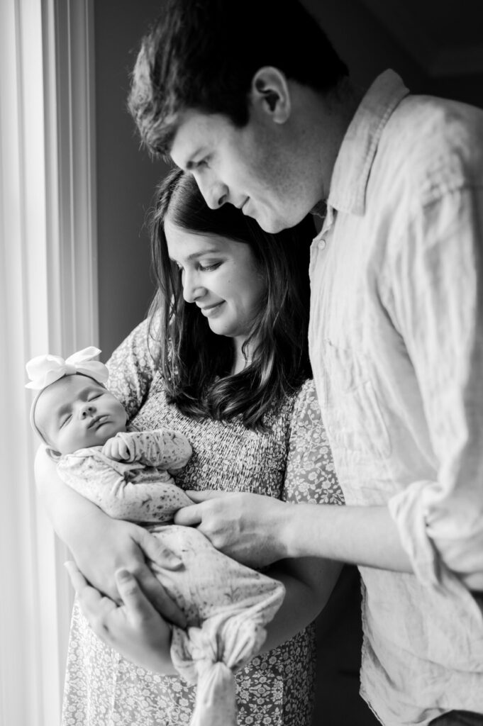 black and white picture of mom holding baby girl and dad standing next to her photographed by NPS Photography