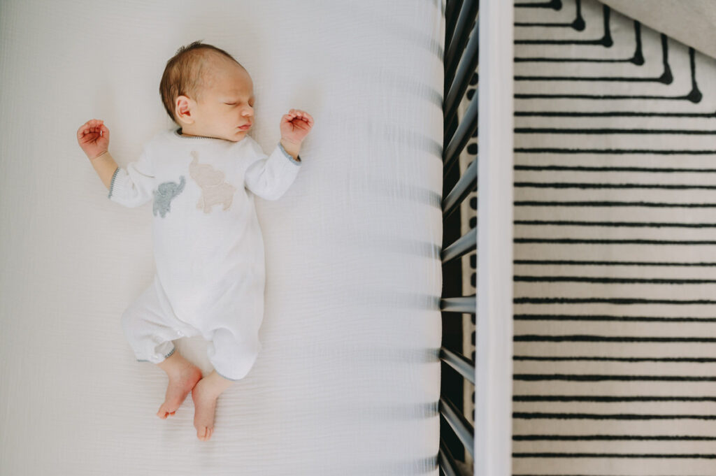 newborn photographed in crib on white sheet by NPS Photography for clutter-free in-home photography session