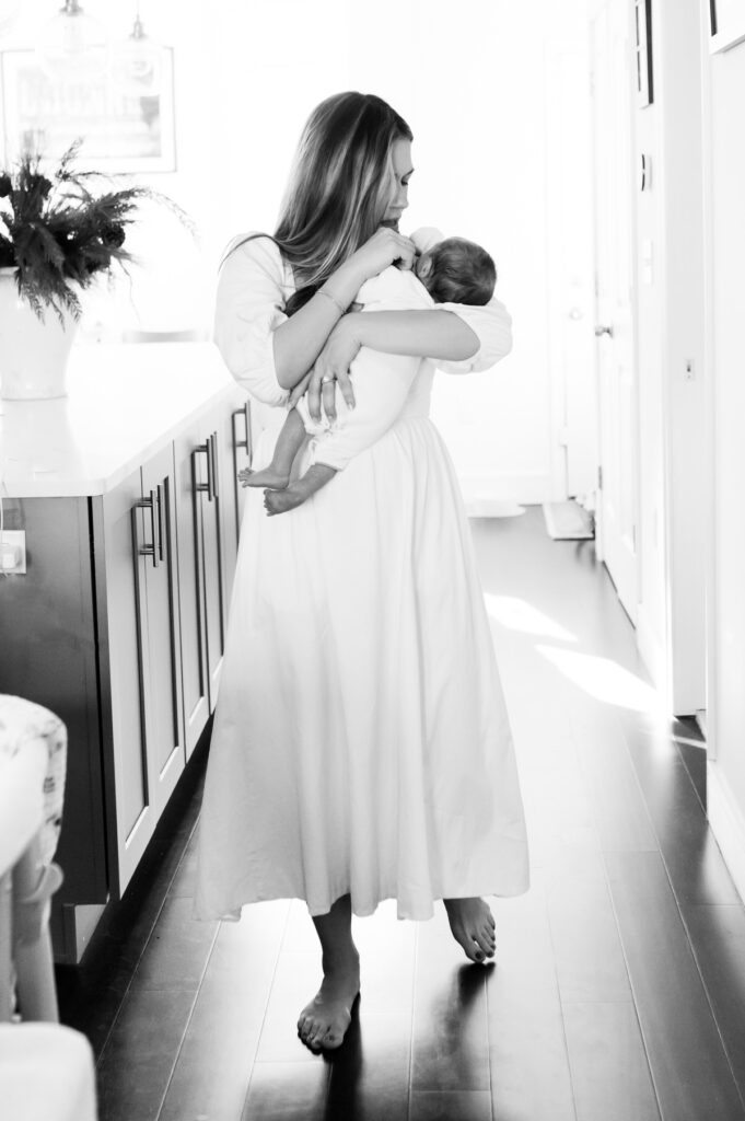 black and white photo of mom walking holding baby photographed by NPS Photography