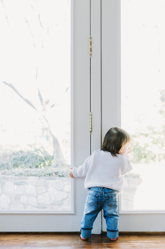 toddler peering out glass doors