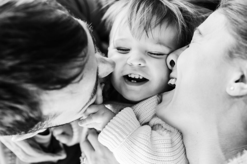 black and white photo of parents kissing a toddler