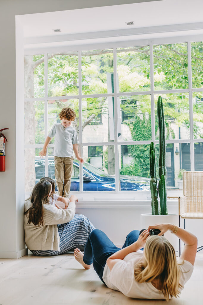 a photographer on the ground photographing a family near an open window