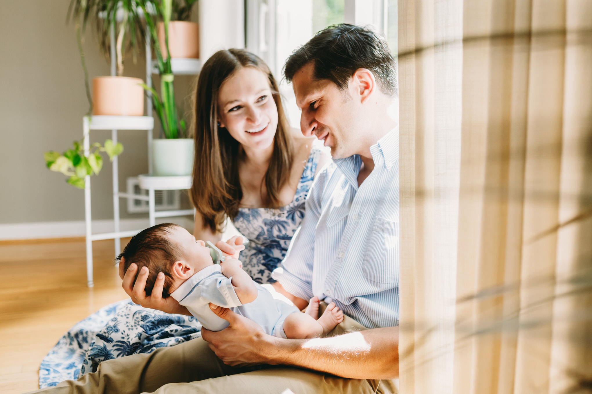Luxury Family Photographer Pricing: You Are Not Your Client’s Budget Coach - NPS Photography mom and dad holding baby while sitting on floor - luxury family photographer pricing