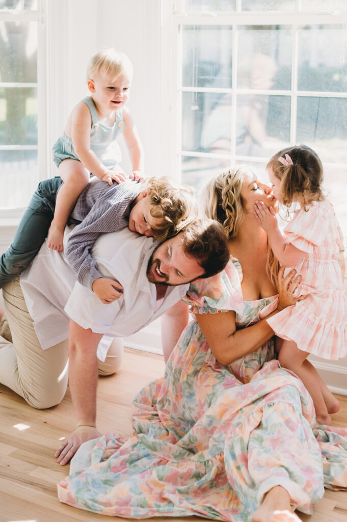 Summer-family-photography-in-DC A playful family moment with kids climbing and kissing during a lively summer family photography in DC session.