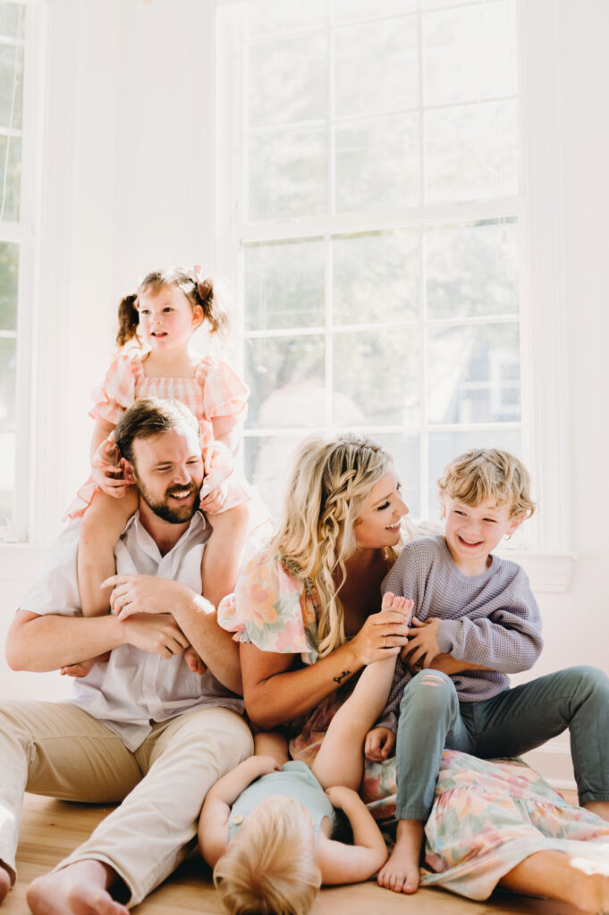 Summer-family-photography-in-DC A happy family sharing playful moments and laughter together in a bright, sunlit room.
