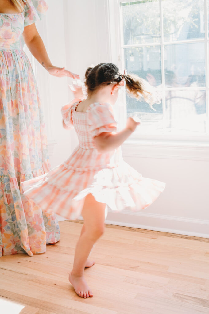 Summer-family-photography-in-DC A little girl twirls happily in a bright room during a joyful summer family photography in DC session.