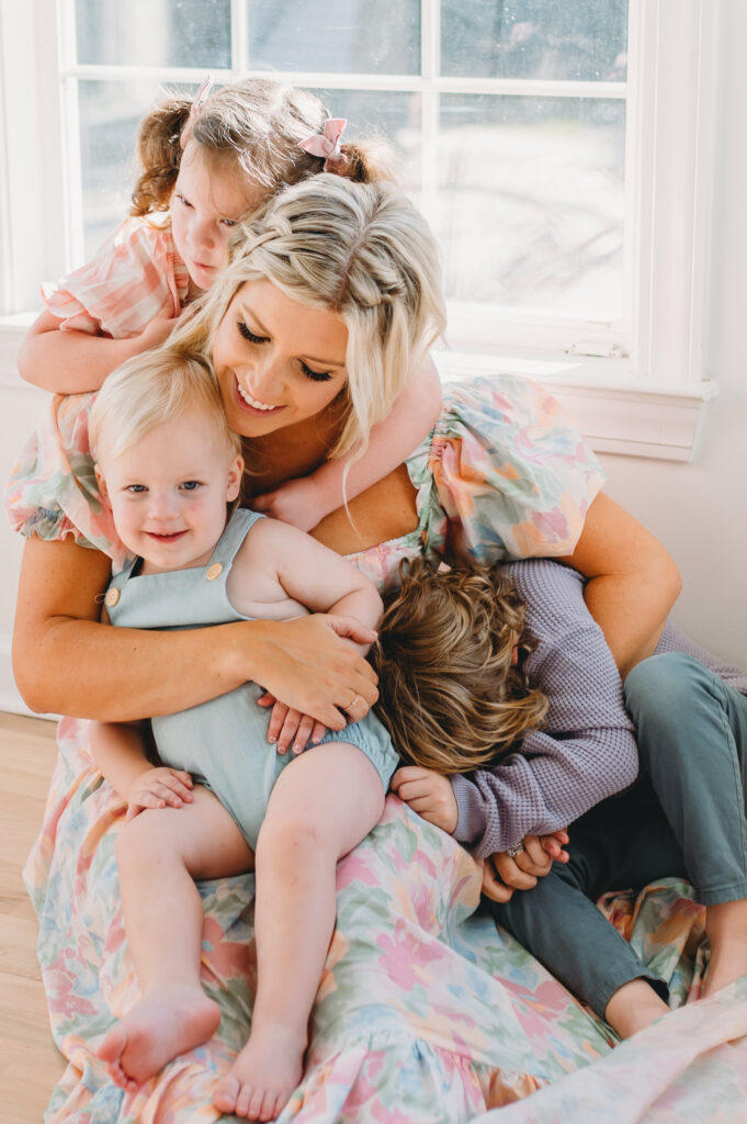 Summer-family-photography-in-DC A loving mother cuddles her happy children in a warm, bright moment during a summer family session.