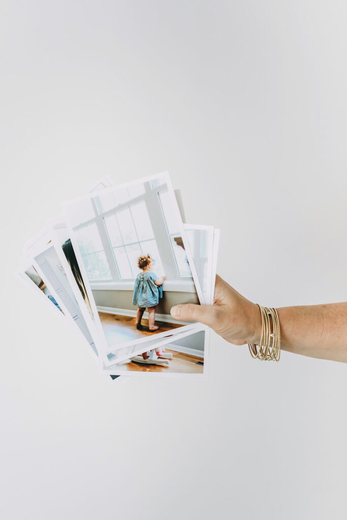 Hand holding printed family photographs—showcasing the type of work to highlight on your contact page.