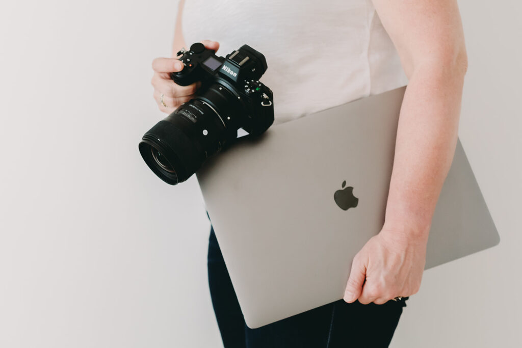 Email Like a Pro: Using AI to Save Time and Strengthen Client Prep as a Photographer - NPS Photography Photographer holding a Nikon camera and MacBook—essential tools to edit, capture, and email like a pro.