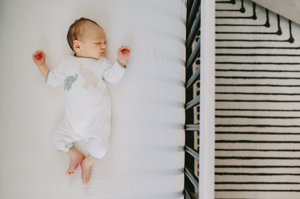 in-home-photo-shoot Newborn peacefully sleeps in a cozy crib during a warm and natural in-home photo shoot.