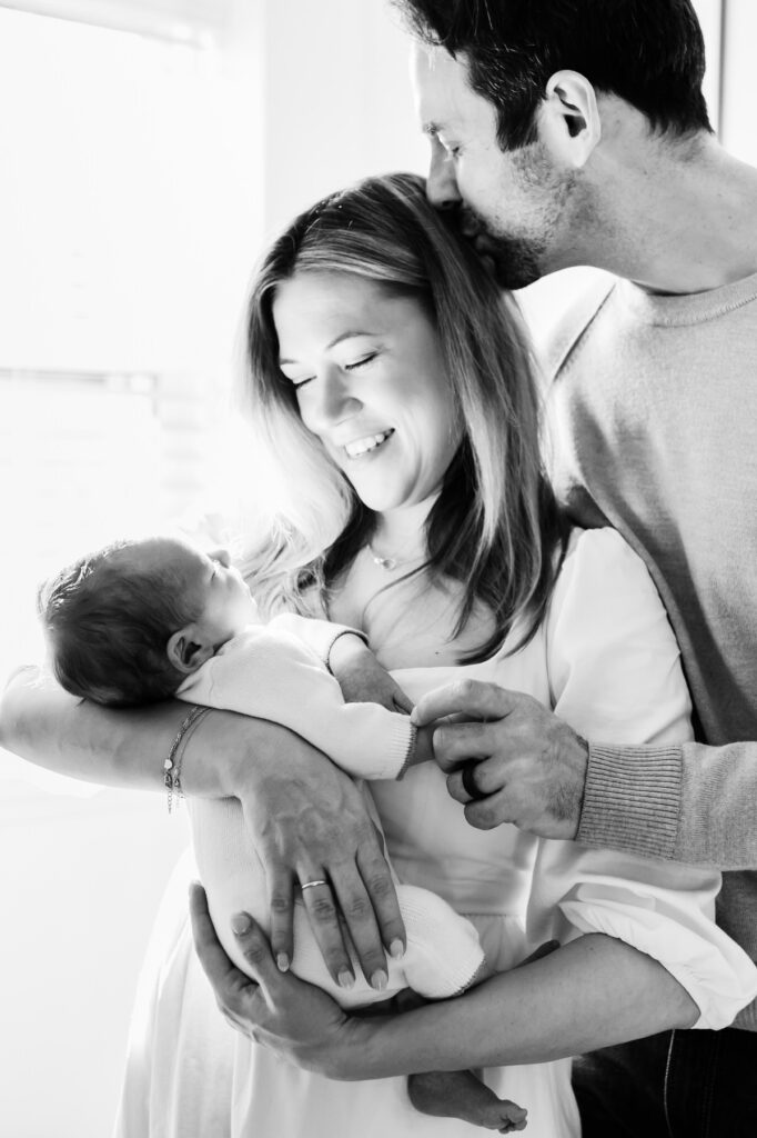 in-home-photo-shoot A tender moment captured during an intimate black-and-white in-home photo shoot with a newborn and parents.