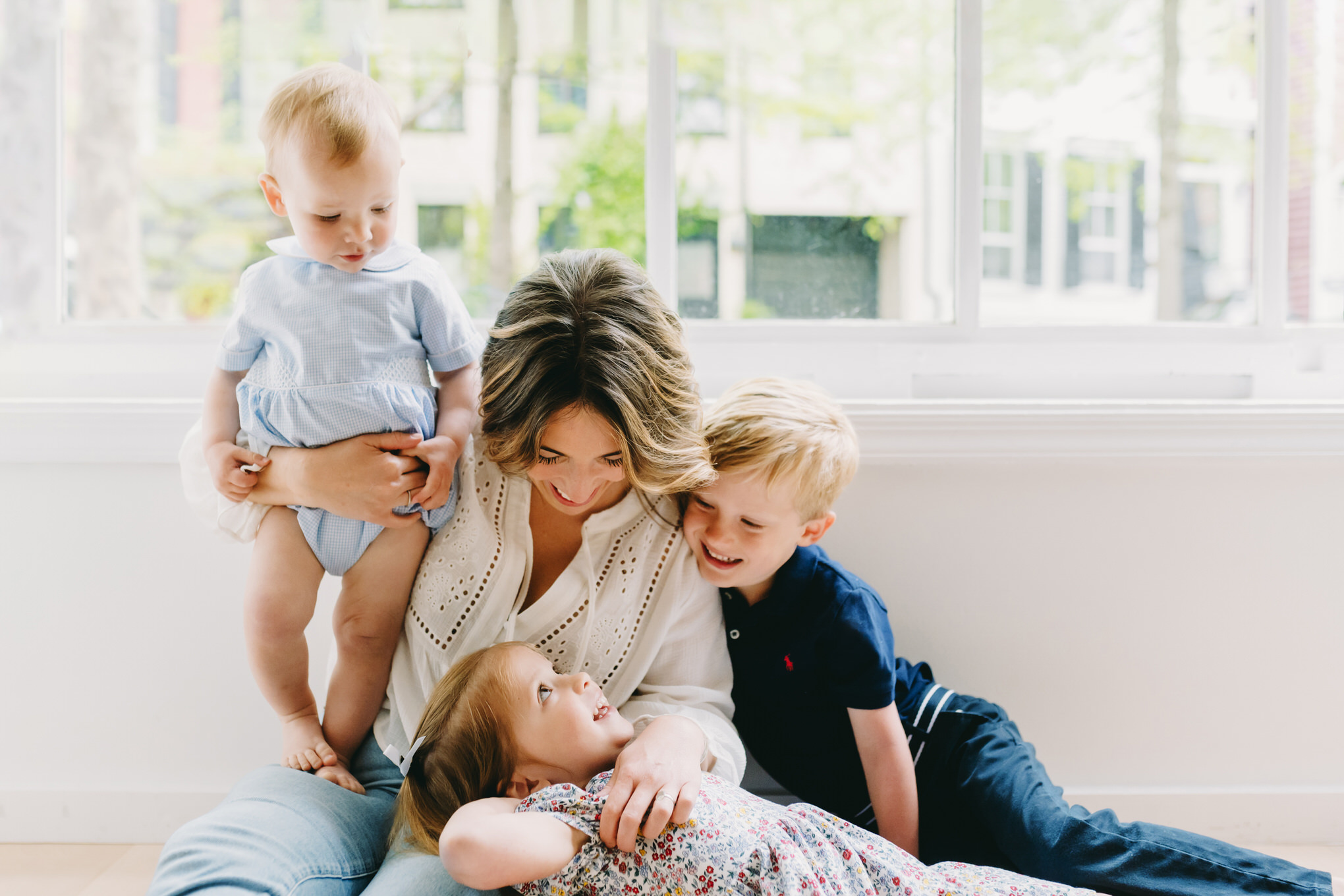 photography-prompts-for-kids A joyful mom cuddles her three kids, capturing authentic smiles with creative photography prompts for kids.