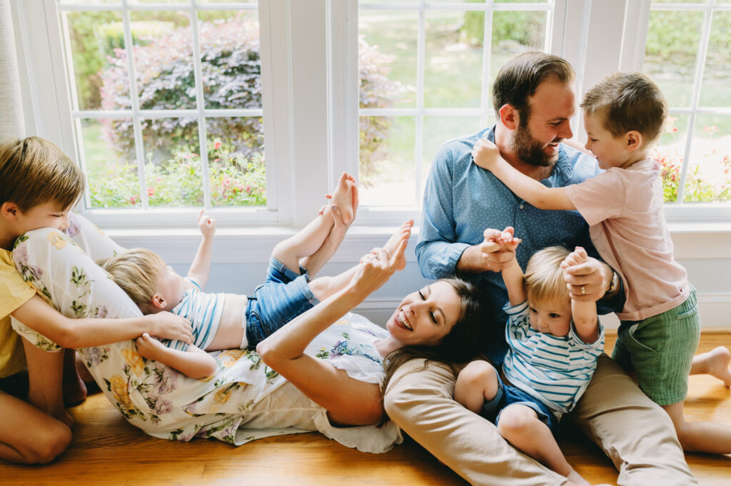 photography-prompts-for-kids A lively family plays and laughs together on the floor, sharing joyful moments full of love and connection.