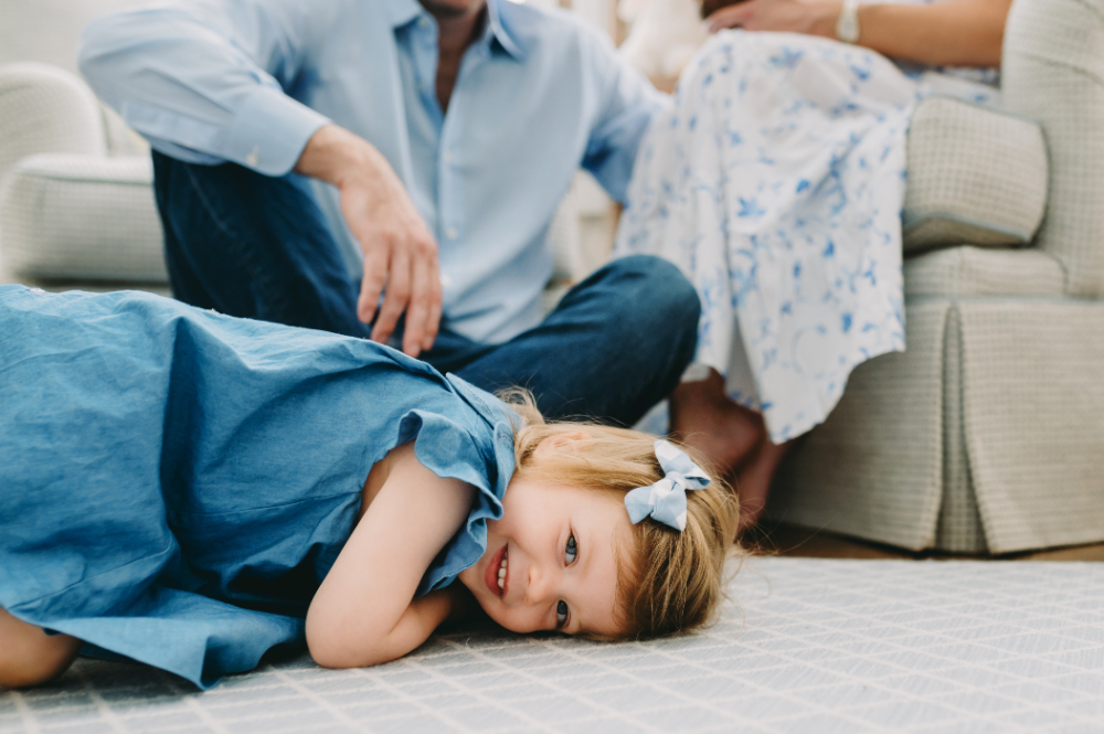 What to Expect After Your Photo Session: A Step-by-Step Guide - NPS Photography Young girl smiles while lying on the rug during a relaxed family moment, perfectly capturing what to expect after your photo session in a cozy home setting.