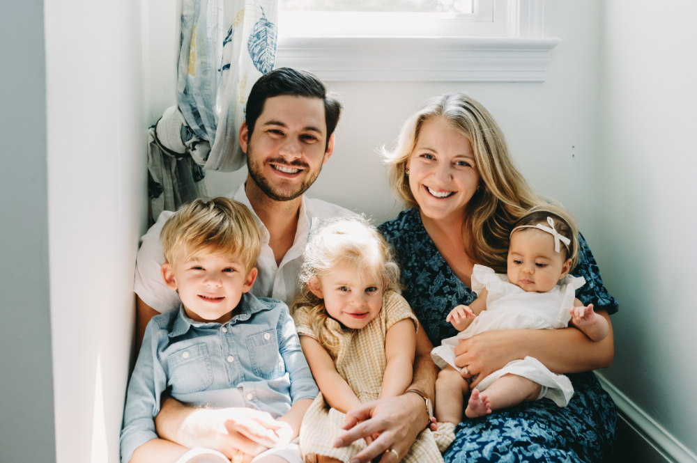 Smiling family of five cuddles together in soft natural light, showcasing what to expect after your photo session when it’s full of warmth and connection.