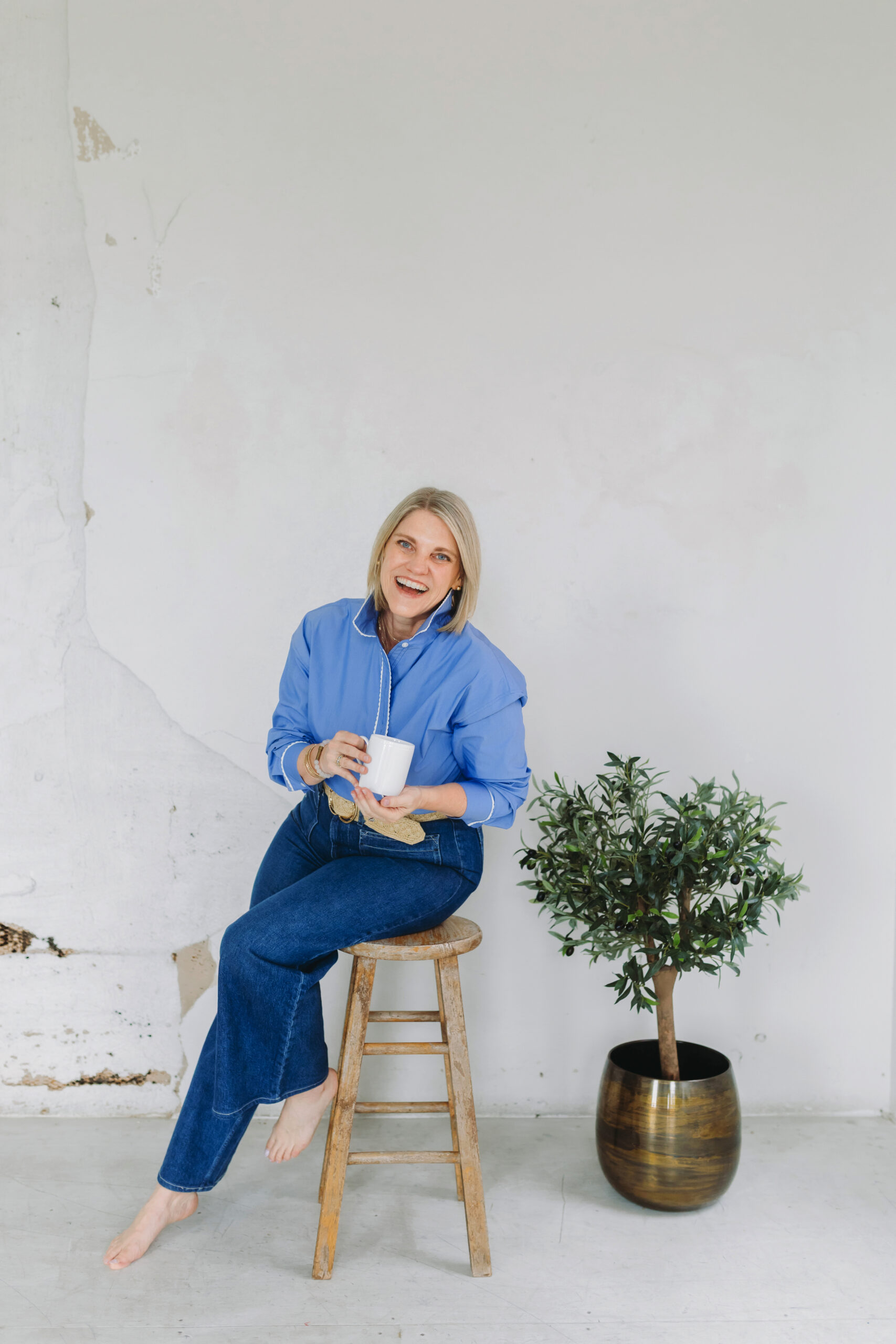 What’s the Best CRM for Photographers? Here’s My 2025 Review - NPS Photography Photographer sitting barefoot on a stool with a coffee cup, showcasing the freedom and balance possible with the best CRM for photographers.