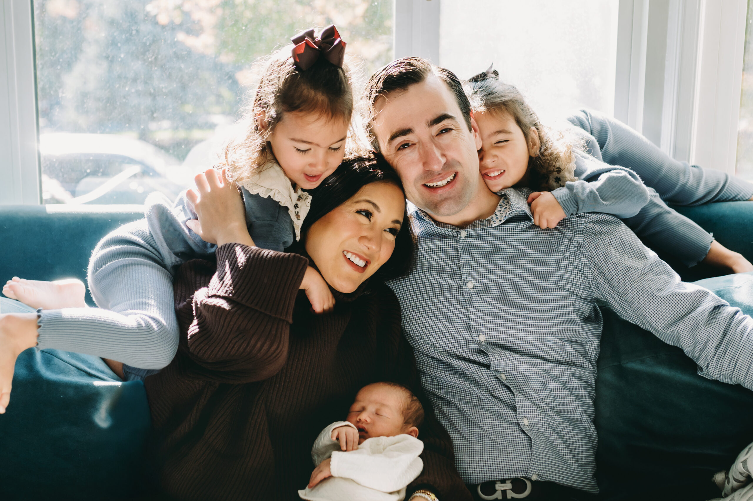 Why Full-Service Family Photography Is Worth Every Penny (And Then Some) - NPS Photography Family cuddles on their living room couch during a full-service family photography session in their home.