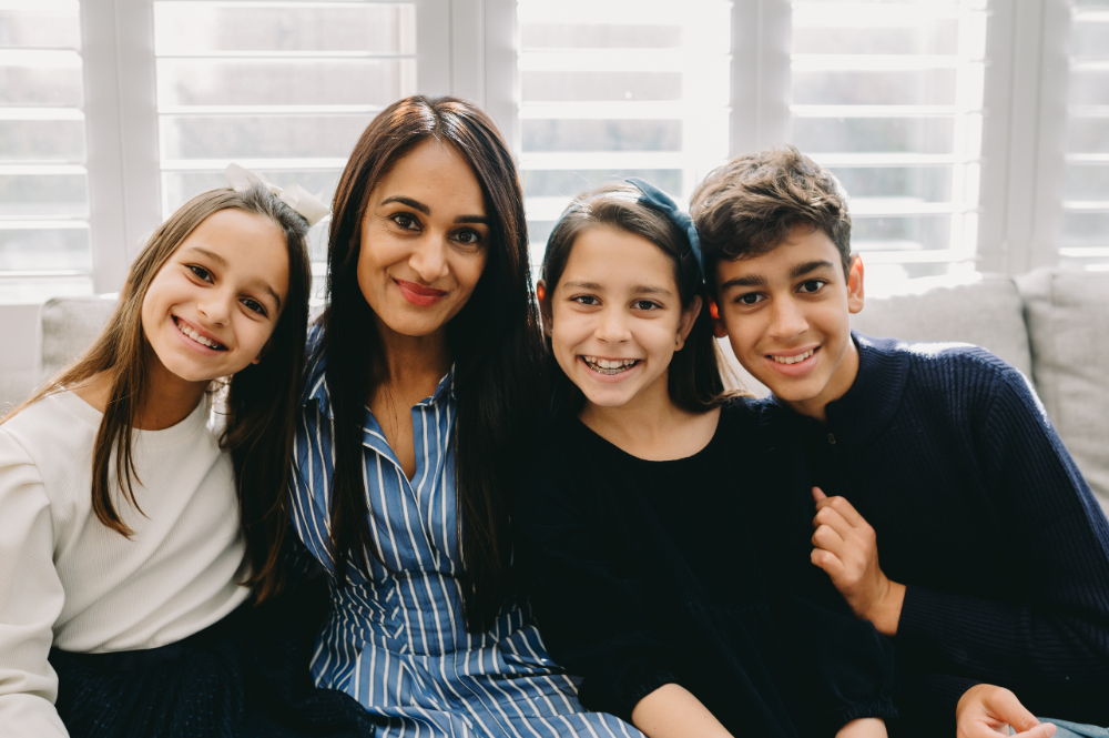 Why Full-Service Family Photography Is Worth Every Penny (And Then Some) - NPS Photography Mom smiles with her three children during a calm, connection-focused lifestyle session in their family room.