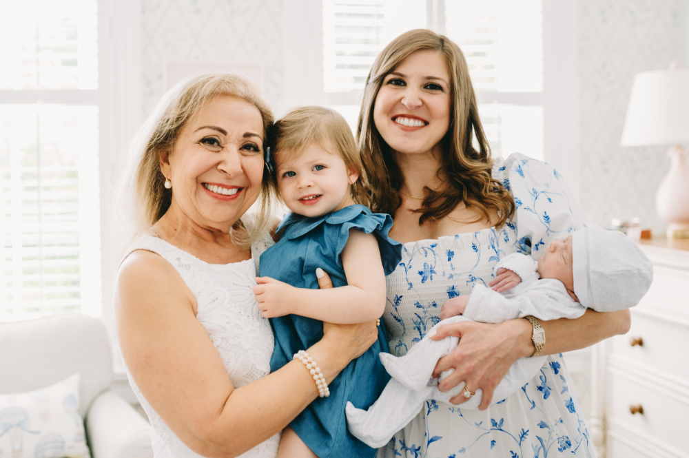 Motherhood Photography at Home: Capturing the Beautiful Chaos of Everyday Life - NPS Photography Three generations smiling together during a motherhood photography session, featuring a grandmother, mom, toddler, and newborn in a bright nursery.