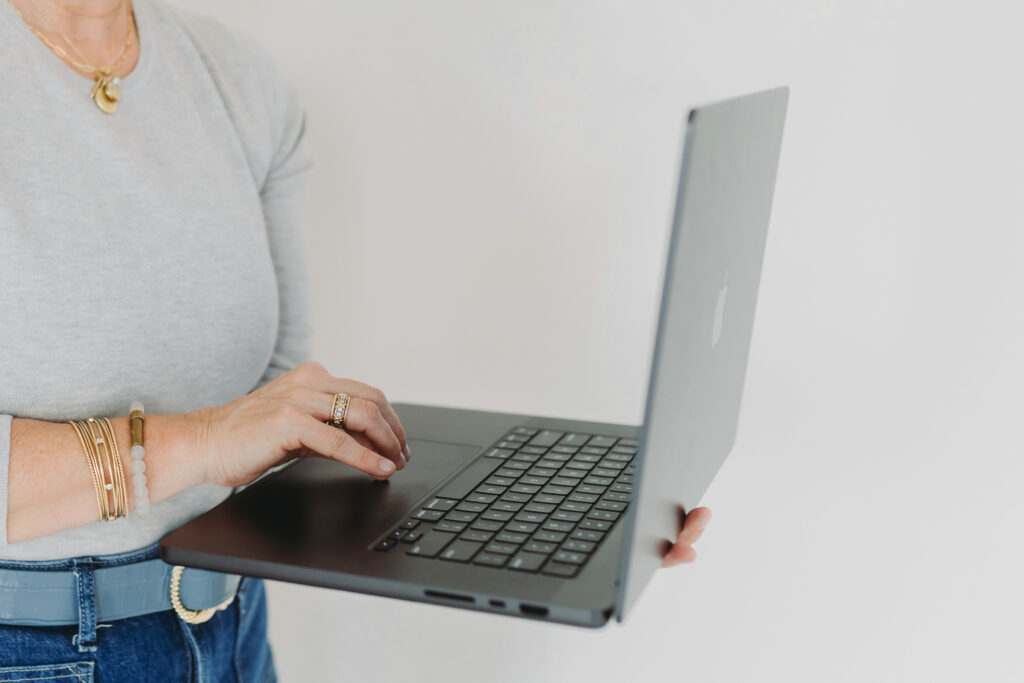 Close-up of a photographer’s hands typing on a laptop, managing business tasks with creativity and consistency.
