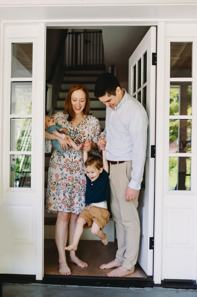 Family of four at the front door, playing and smiling during an in-home family photography session.- fall photography tips