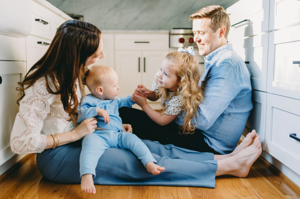 Your Top Questions About In-Home Family Photography, Answered! - NPS Photography Parents and young children playing on the kitchen floor during an in-home family photography session, highlighting natural family connection.