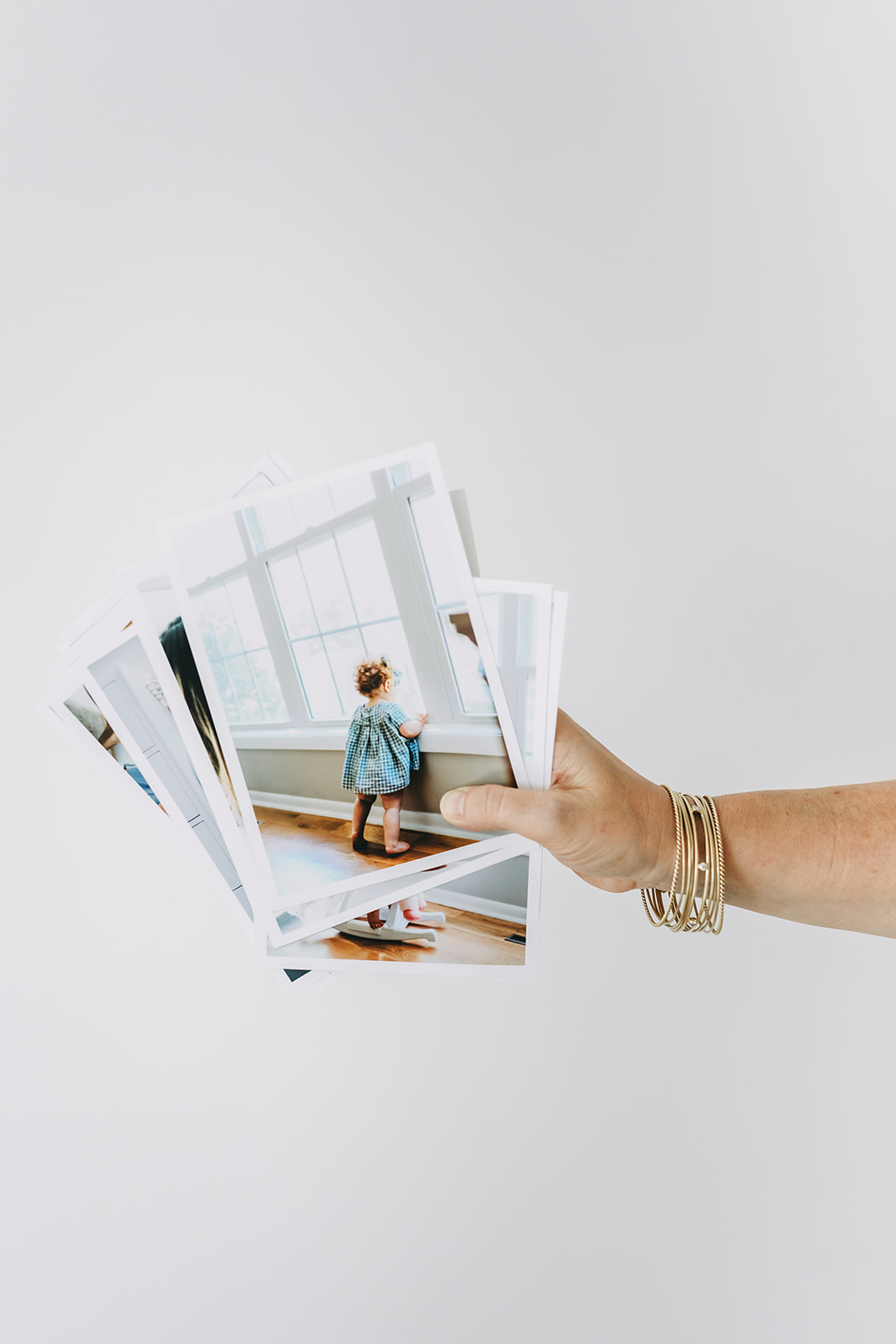 Family Photo Gift Ideas Your Loved Ones Will Treasure This Holiday Season - NPS Photography Hand holding fine art photo prints of a child by the window, showcasing family photo gift ideas for holiday keepsakes.