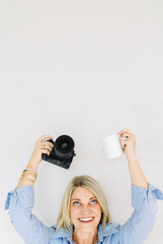 Low-Light Indoor Photography Tips: Shooting During Fall & Winter - NPS Photography Playful photographer raising a camera and coffee mug, celebrating creativity while teaching low-light indoor photography tips for winter sessions.