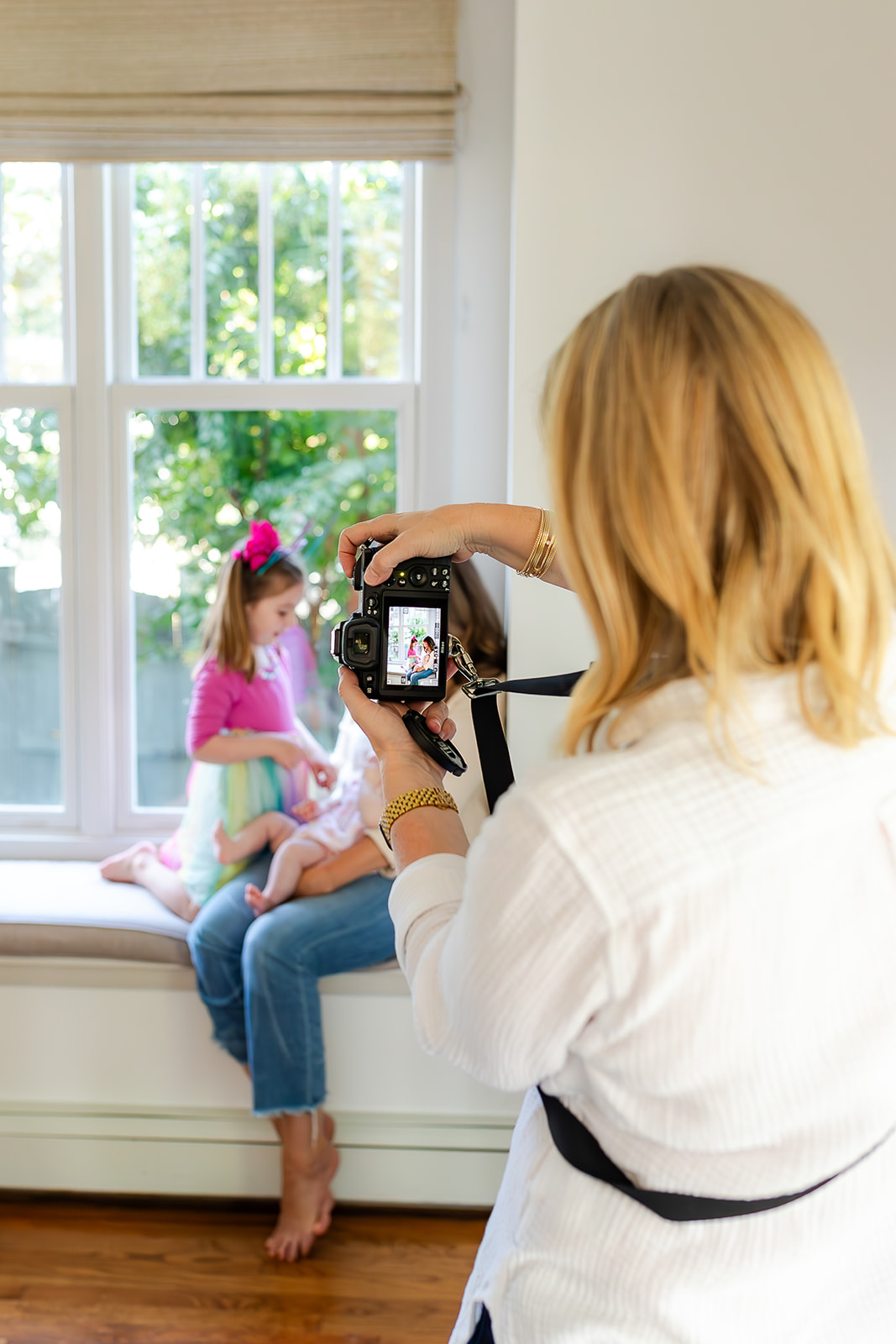 A photographer capturing a tender sibling moment by a bright window, giving a peek behind the lens at how she documents real family interactions.