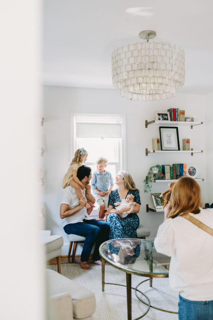A photographer photographing a family cuddled together in a cozy room, showing the heart of her work behind the lens during lifestyle sessions.