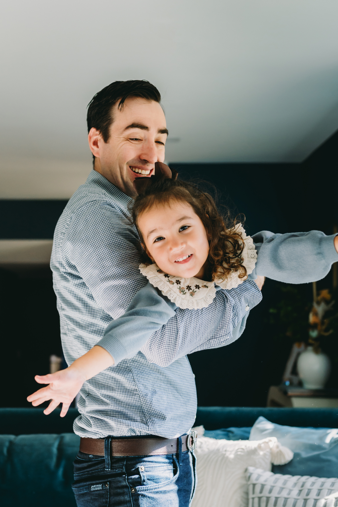 Family Picture Outfits: Your Guide to the Best Photography Looks in the DMV - NPS Photography A father lifting his daughter with joyful energy, both dressed in comfortable family picture outfits that fit a relaxed in-home session.