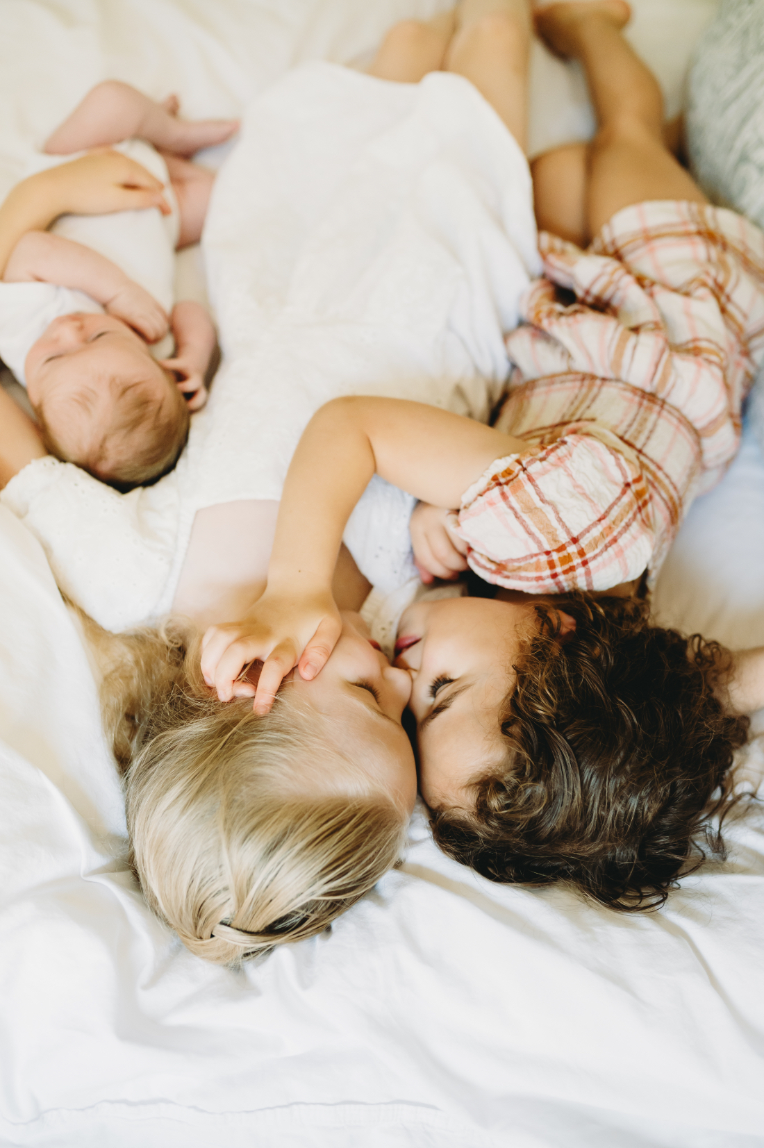 Family Picture Outfits: Your Guide to the Best Photography Looks in the DMV - NPS Photography Three young siblings cuddled together on a bed, showing how simple, neutral family picture outfits help keep the focus on their sweet connection.