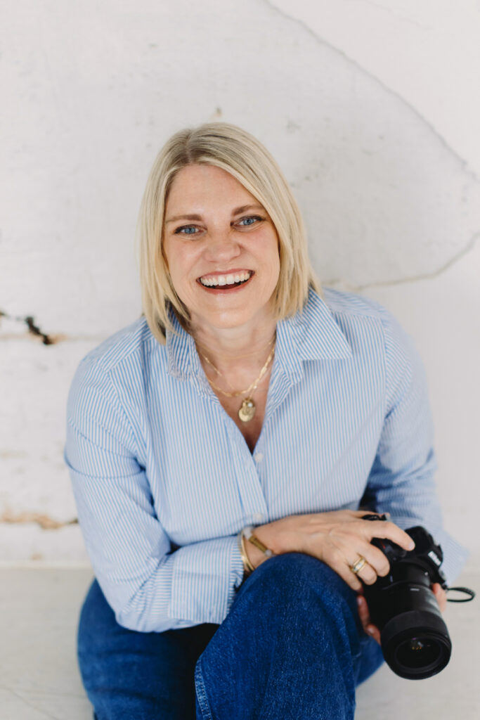 A bright portrait of Natasha smiling and holding her camera, reflecting the confidence and clarity that come from applying solid photography business tips.