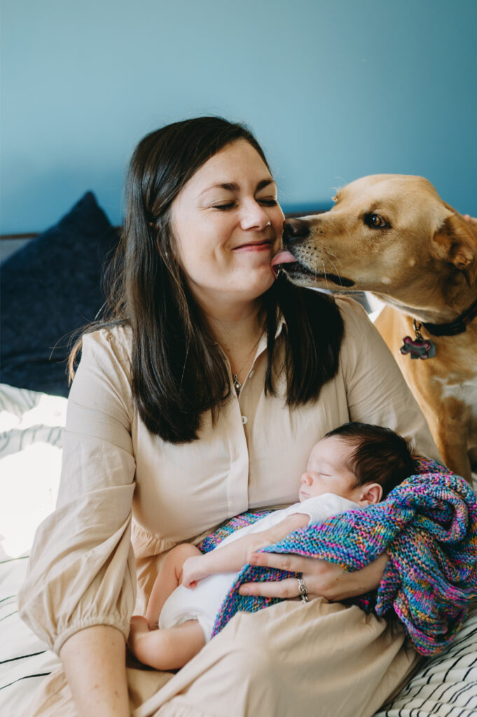 What Is Storytelling Photography? The Heartfelt Secret to Capturing Your Family’s Most Meaningful Moments - NPS Photography A mama snuggling her newborn while the family dog climbs in for a kiss — a perfect glimpse into what real, everyday love looks like in the early days and a beautiful example of what is storytelling photography.