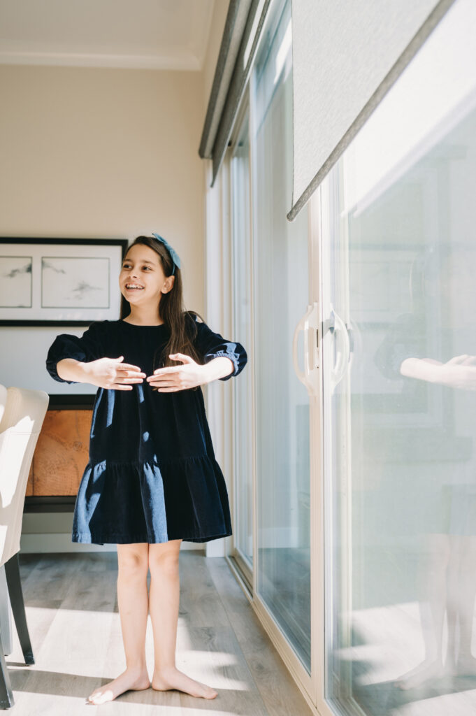 What Is Storytelling Photography? The Heartfelt Secret to Capturing Your Family’s Most Meaningful Moments - NPS Photography A little girl dancing barefoot in the sunlight pouring through the sliding doors, showing how children naturally shine when they’re free to move and be themselves.
