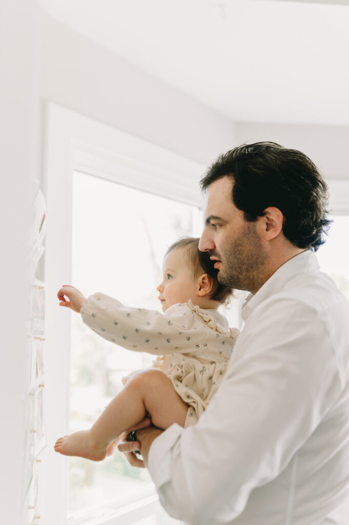 dad holding little girl and looking at photos - family photo session tips