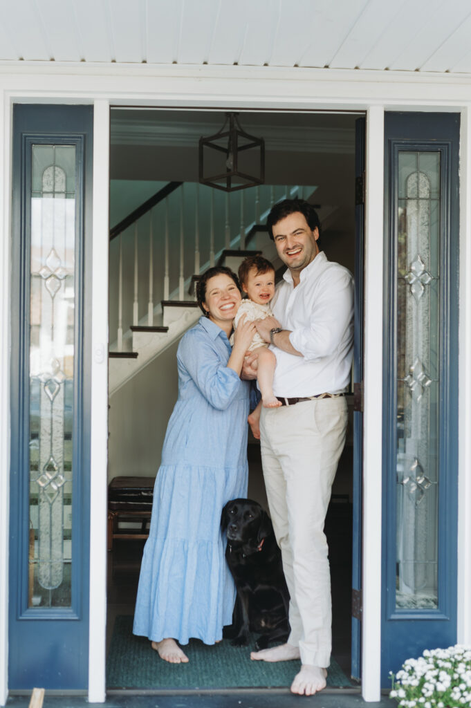 family with little girl and black lab standing in frondoor way